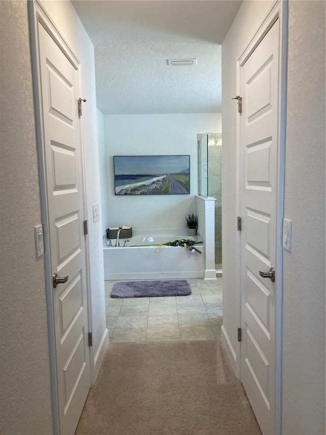 corridor featuring light colored carpet and a textured ceiling