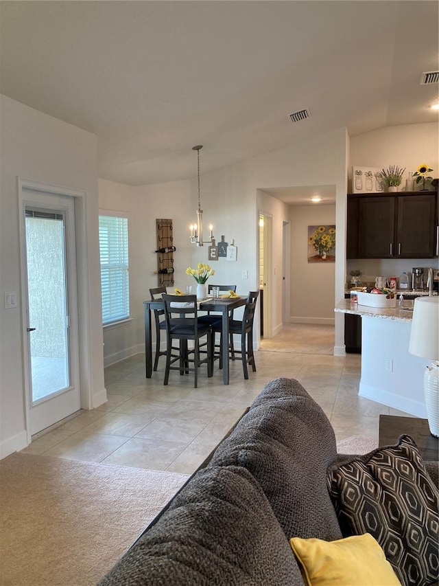 dining area with a notable chandelier, lofted ceiling, and light tile patterned floors