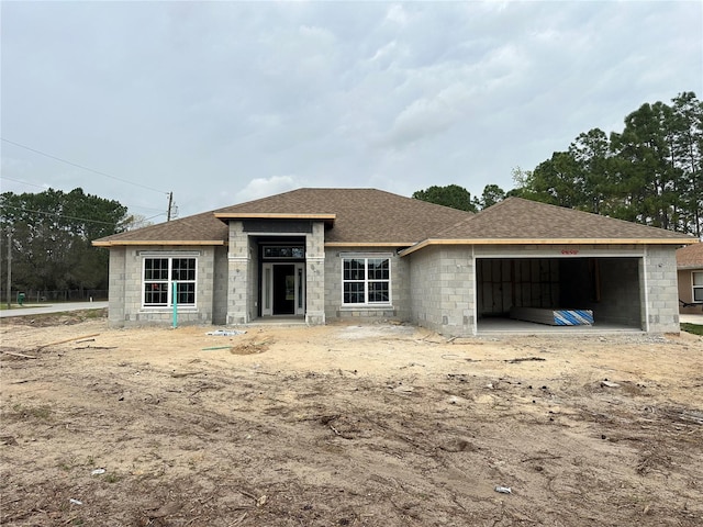 view of front of house with concrete block siding, an attached garage, and a shingled roof