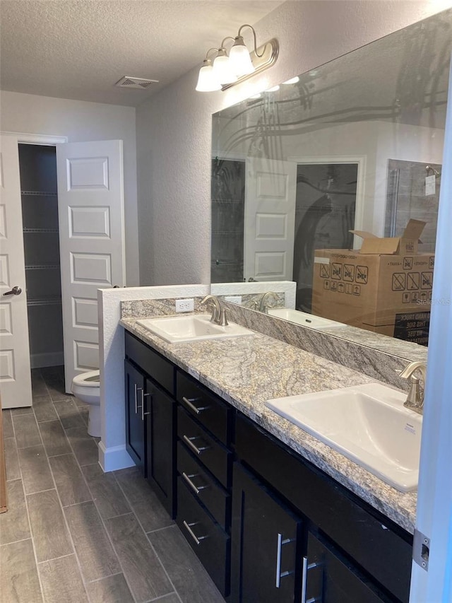 bathroom with vanity, toilet, and a textured ceiling