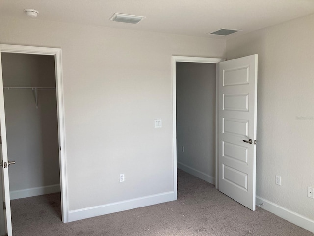 unfurnished bedroom with light carpet, a walk in closet, and a closet