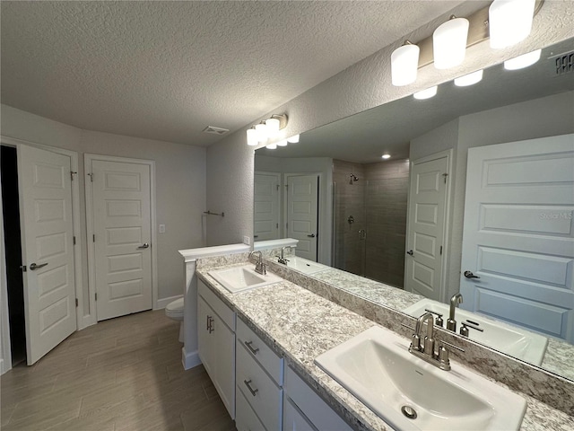 bathroom with an enclosed shower, vanity, a textured ceiling, and toilet