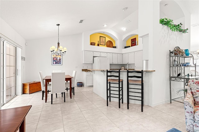 tiled dining space featuring a notable chandelier and high vaulted ceiling