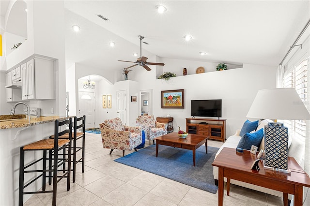 living room with light tile patterned flooring, high vaulted ceiling, sink, and ceiling fan with notable chandelier