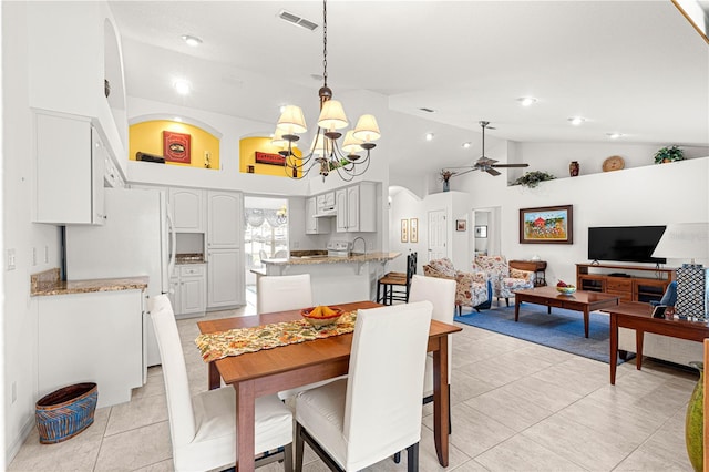 tiled dining room with high vaulted ceiling, sink, and ceiling fan with notable chandelier