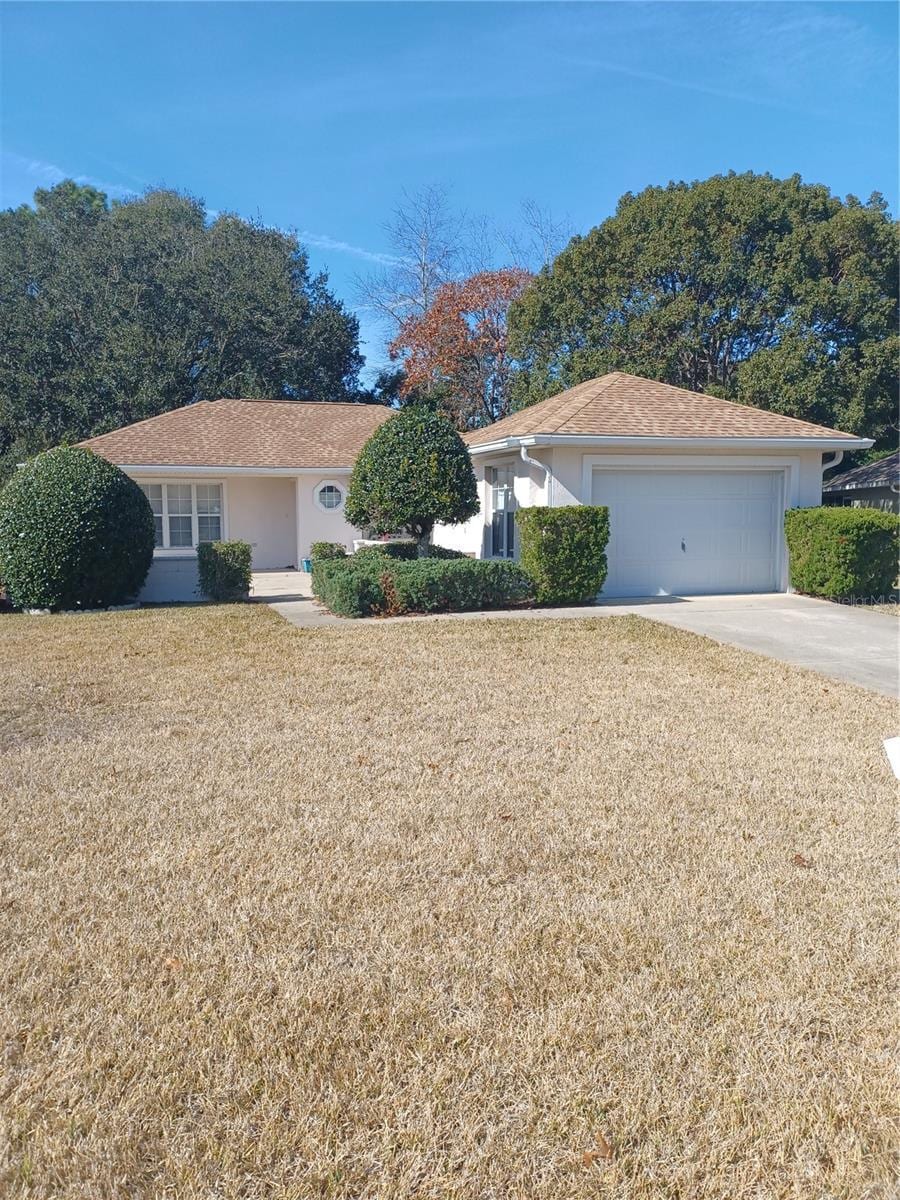 single story home with a garage and a front lawn