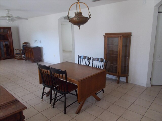 dining area featuring light tile patterned floors, arched walkways, and ceiling fan