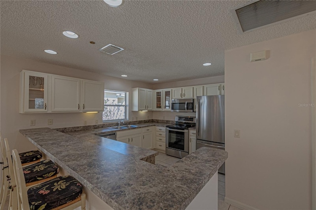 kitchen featuring sink, white cabinets, a kitchen breakfast bar, kitchen peninsula, and stainless steel appliances