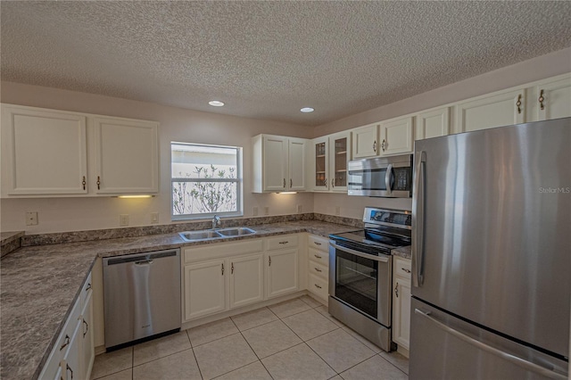 kitchen featuring light tile patterned flooring, sink, white cabinets, stainless steel appliances, and a textured ceiling