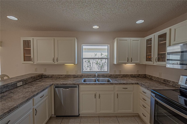 kitchen featuring light tile patterned flooring, sink, white cabinets, stainless steel appliances, and a textured ceiling