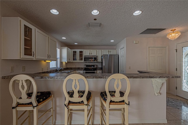 kitchen with sink, light tile patterned floors, a breakfast bar, white cabinetry, and stainless steel appliances