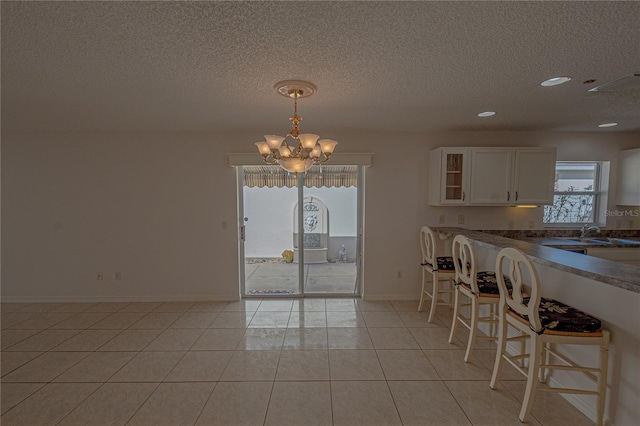 tiled dining room with an inviting chandelier and a textured ceiling