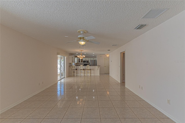 unfurnished room featuring ceiling fan with notable chandelier, a textured ceiling, and light tile patterned floors