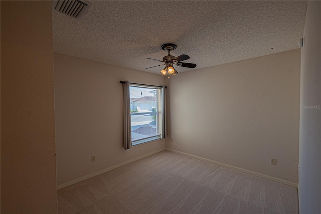 spare room with ceiling fan, light carpet, and a textured ceiling