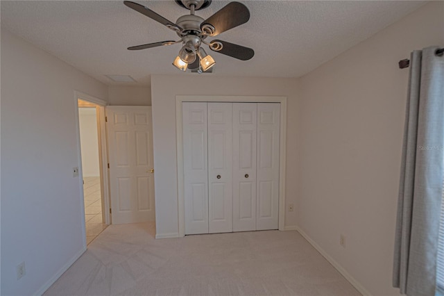 unfurnished bedroom featuring ceiling fan, light carpet, a textured ceiling, and a closet