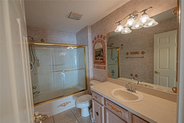 full bathroom featuring bath / shower combo with glass door, tile patterned flooring, vanity, toilet, and a textured ceiling