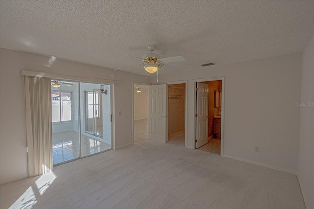 unfurnished room featuring ceiling fan, light colored carpet, and a textured ceiling