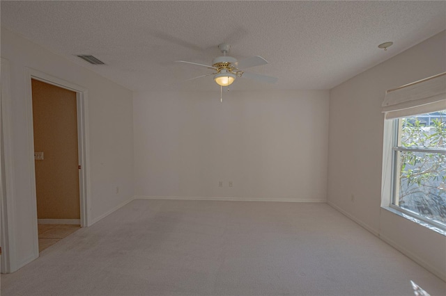 spare room with ceiling fan, light carpet, and a textured ceiling