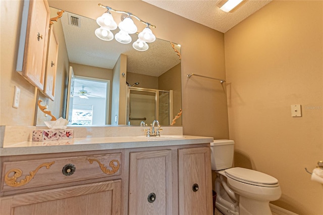 bathroom featuring vanity, toilet, a shower with door, and a textured ceiling