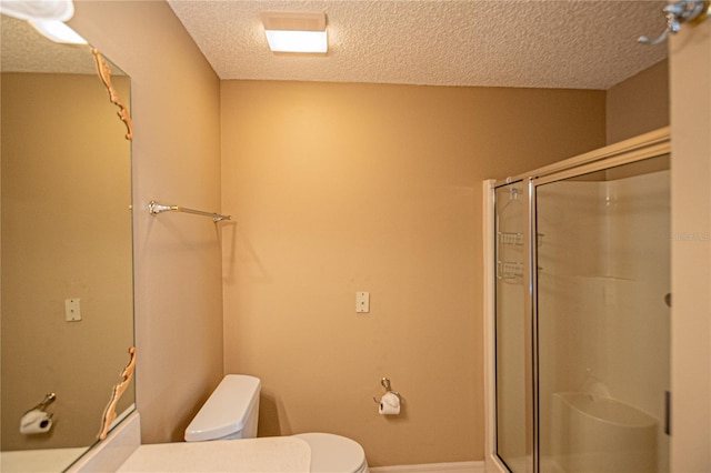 bathroom with toilet, a shower with door, and a textured ceiling