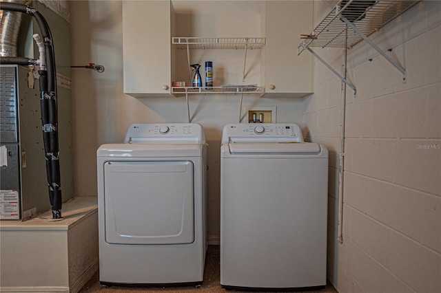 clothes washing area with cabinets and washer and clothes dryer