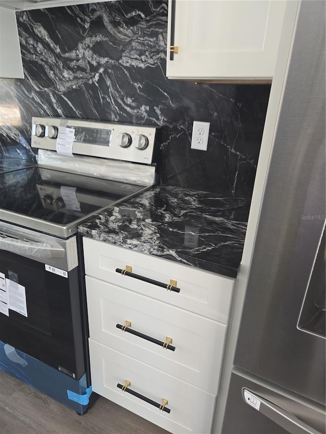 kitchen with tasteful backsplash, dark hardwood / wood-style flooring, white cabinets, and appliances with stainless steel finishes