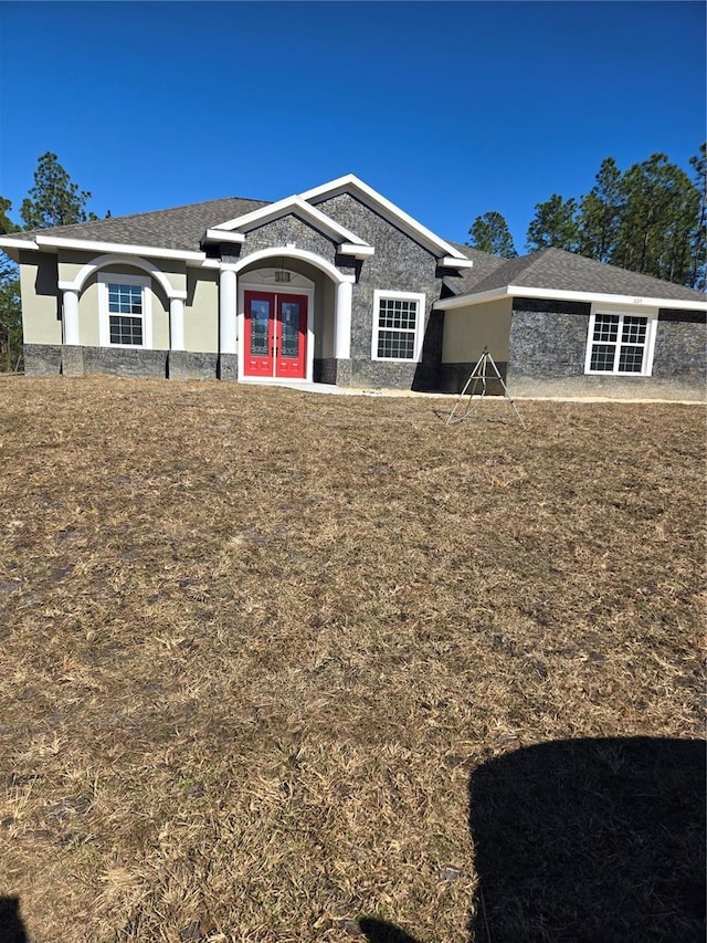 view of front of property with french doors and a front lawn