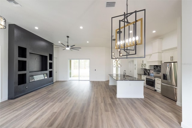 kitchen with white cabinetry, decorative light fixtures, appliances with stainless steel finishes, a fireplace, and light hardwood / wood-style floors