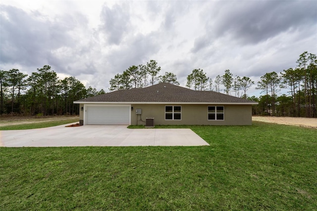 rear view of house with a garage, central AC unit, and a lawn