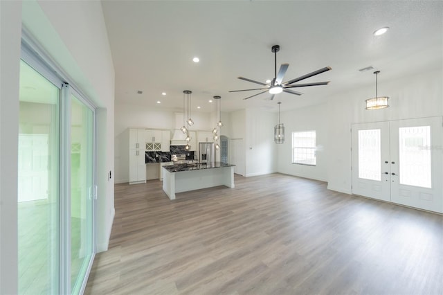 unfurnished living room featuring light hardwood / wood-style floors, french doors, and ceiling fan