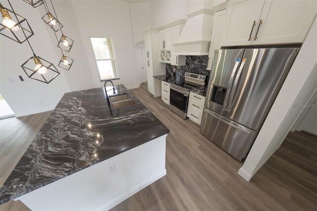 kitchen featuring sink, premium range hood, white cabinetry, hanging light fixtures, and appliances with stainless steel finishes