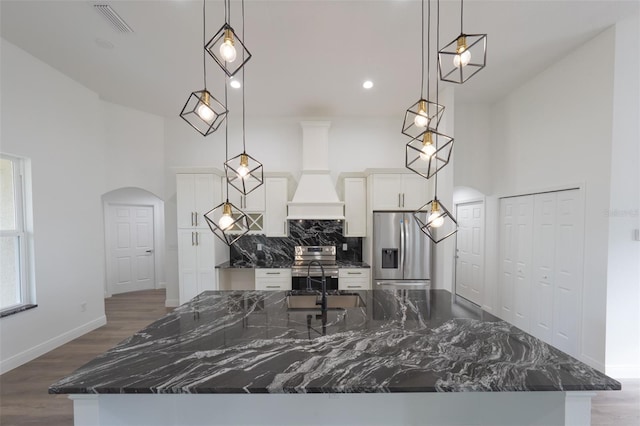 kitchen with appliances with stainless steel finishes, decorative light fixtures, white cabinets, and dark stone counters