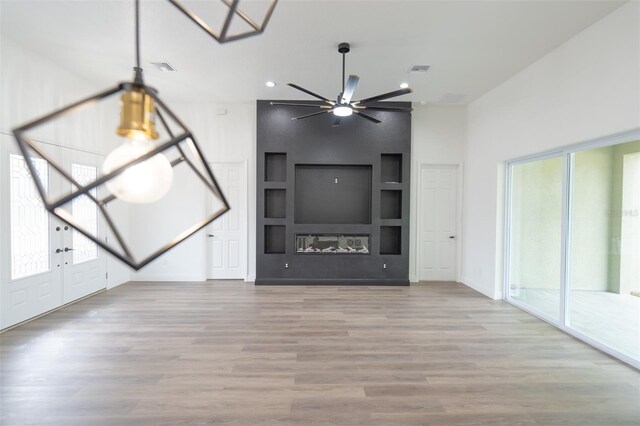 unfurnished living room with built in shelves, a healthy amount of sunlight, and light hardwood / wood-style flooring