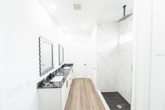 interior space with hardwood / wood-style flooring, vanity, and a tile shower