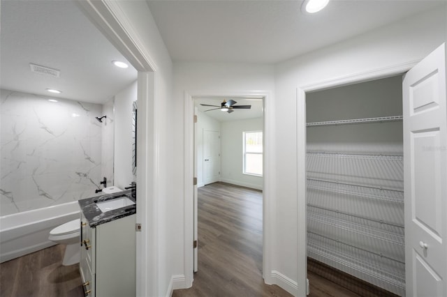 full bathroom with vanity, hardwood / wood-style floors, tiled shower / bath, and toilet