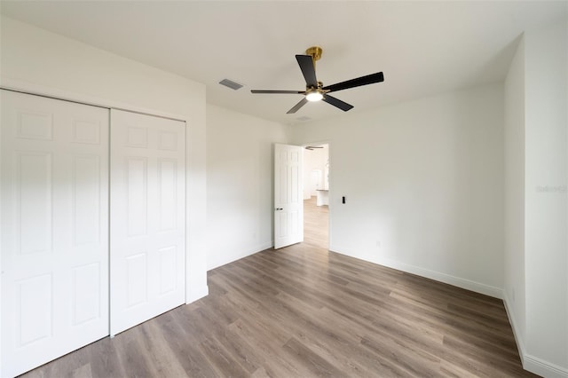 unfurnished bedroom featuring wood-type flooring, a closet, and ceiling fan