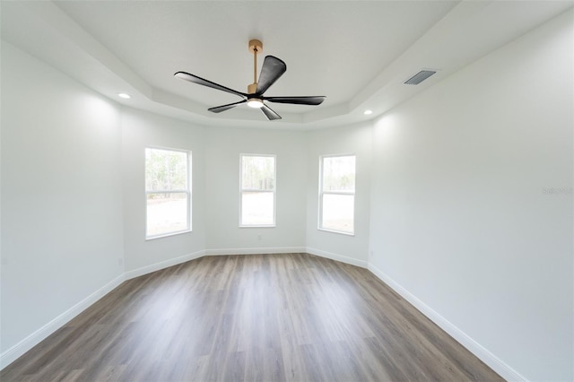 unfurnished room with wood-type flooring, a raised ceiling, and ceiling fan