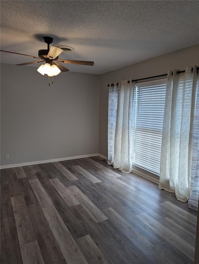 unfurnished room with ceiling fan, baseboards, dark wood finished floors, and a textured ceiling