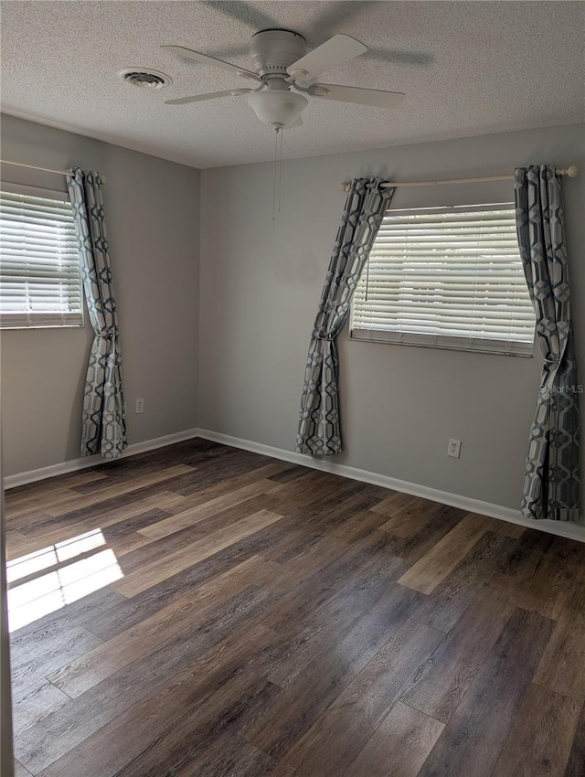 unfurnished room with visible vents, a textured ceiling, baseboards, and wood finished floors