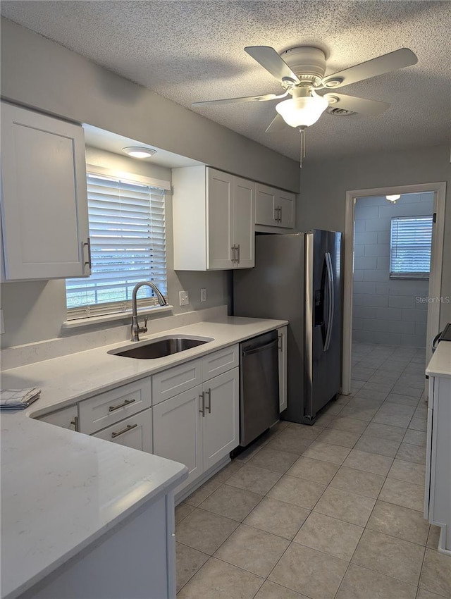 kitchen featuring dishwasher, white cabinetry, light countertops, and a sink