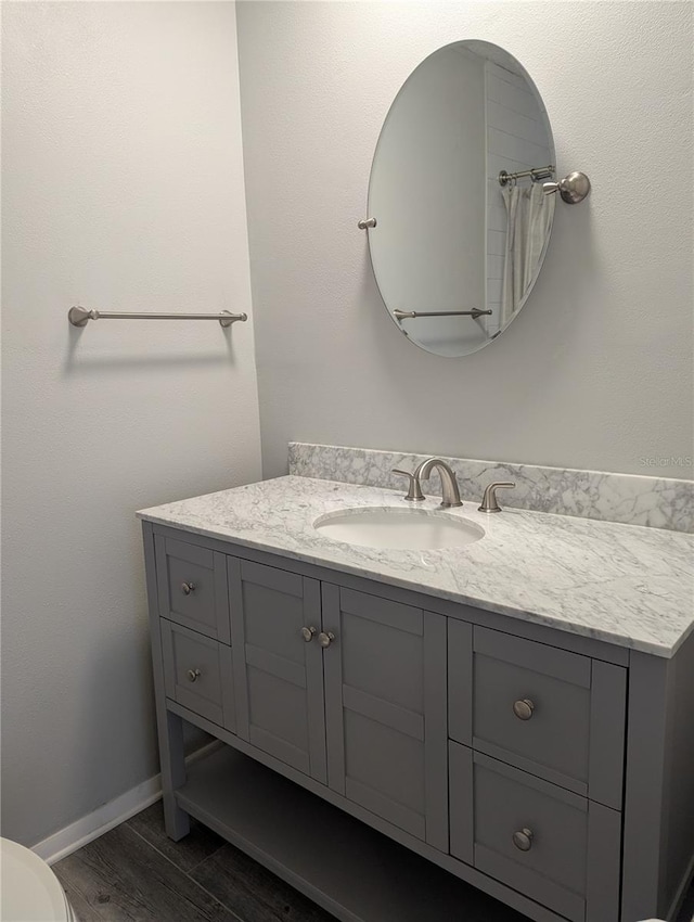 full bathroom with toilet, wood finished floors, vanity, and baseboards