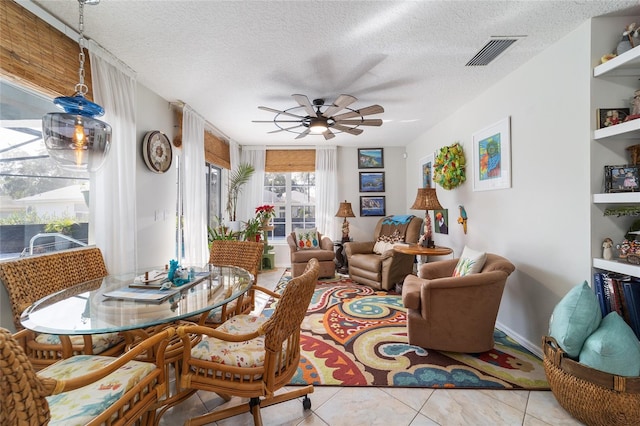 living room featuring ceiling fan, a textured ceiling, and light tile patterned floors