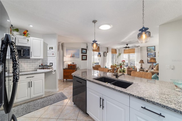 kitchen featuring pendant lighting, sink, black dishwasher, white cabinets, and light stone countertops