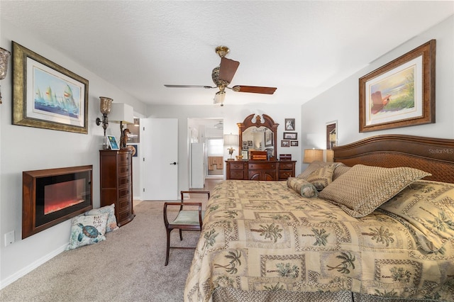 bedroom featuring ceiling fan, light colored carpet, ensuite bathroom, and a textured ceiling