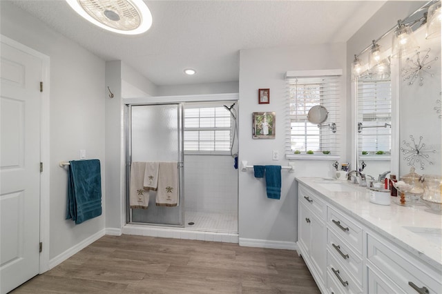 bathroom featuring vanity, wood-type flooring, a shower with shower door, and a textured ceiling