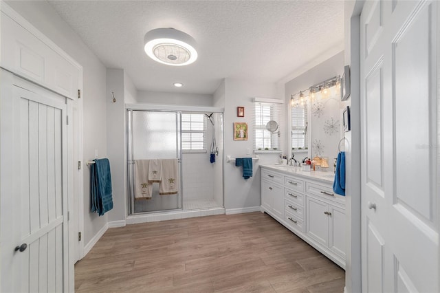 bathroom with vanity, a textured ceiling, a shower with shower door, and wood-type flooring