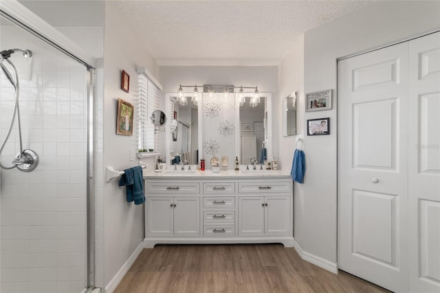 bathroom with hardwood / wood-style flooring, vanity, a shower with door, and a textured ceiling