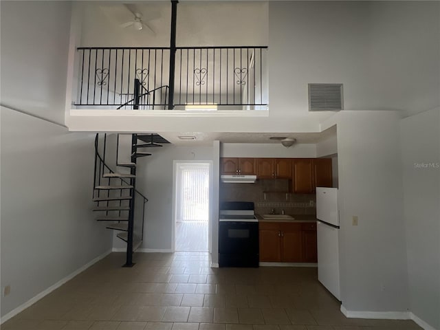 kitchen with sink, black range with electric stovetop, a high ceiling, tasteful backsplash, and white fridge