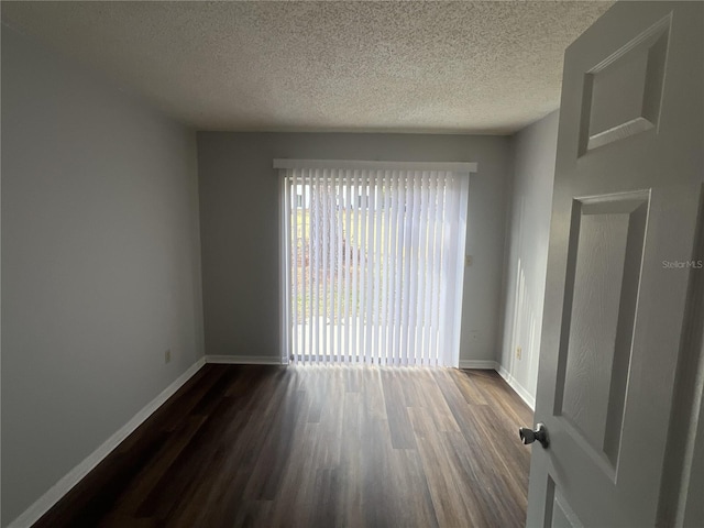 empty room with dark hardwood / wood-style floors and a textured ceiling