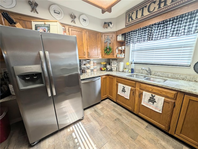 kitchen with stainless steel appliances, sink, light stone counters, and light wood-type flooring